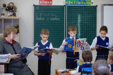 Öğrenciler ders sırasında sınıftaki tahtanın yanında ders kitapları okurlar. İlköğretim. Seçici odaklanma. Rusya, Novosibirsk, 21.01.2021