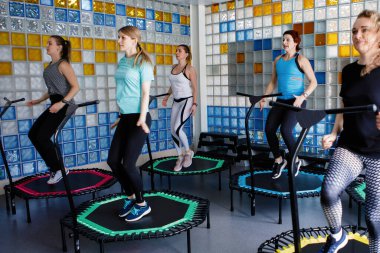 Spor salonunda trambolinde spor yapan bir grup kadın..
