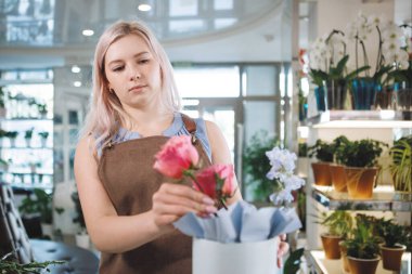 Çiçekçinin atölyesinde önlüklü sarışın kadın. Seçici odak.