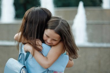 Asyalı anne bir yaz parkında kızını kucaklıyor ve kollarına alıyor. Seçici odaklanma, bulanık arkaplan. Mutlu bir çocukluk. Ebeveyn bakımı.
