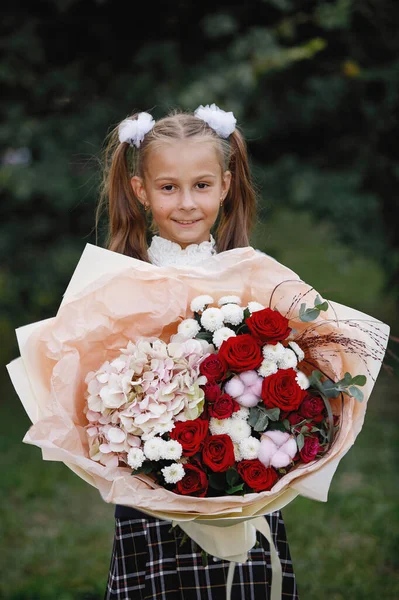 Üniformalı Kız Öğrenci Çiçek Fiyonklu Yeşil Yapraklı Bir Arka Planda — Stok fotoğraf