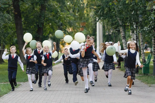 Grupa Uczniów Mundurze Balonami Biegnie Letnim Parku Wybiórcze Skupienie Zamazane — Zdjęcie stockowe