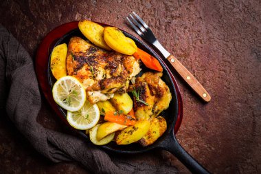 Tavada patates, havuç ve otla servis edilen fırında limonlu tavuk..