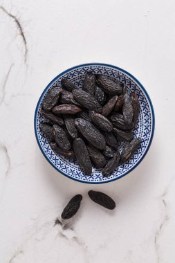 Beyaz arka planda küçük kasede kokulu tonka çekirdekleri, fırında aromalı malzeme (Dipteryx odorata))