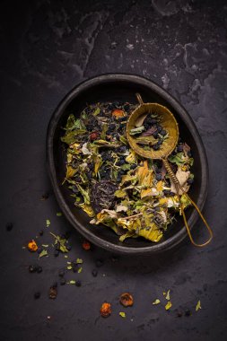 Çay, kurutulmuş organik çay ve meyve karışımı ve siyah arka planda çay süzgeci.