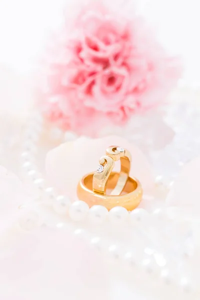 金光闪闪的结婚戒指 背景为珍珠项链 背景为粉红花朵 焦点柔和 — 图库照片