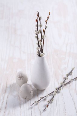 Pussy willow branches in vase with Easter egg on wooden kitche table. Easter table decoration.