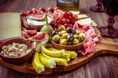 Charcuterie, İtalyan salamı, peyniri, camembert peyniri ve ahşap masada zeytin içeren antipasti tabağı. 