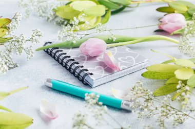 Çalışma alanı günlük, defter, kalem, açık mavi arka planda çiçekler. Merkez ofis masası. Üst görünüm kadınsı arka plan. Düz yatış, üst görünüm.