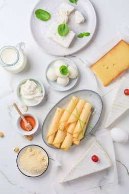 Beyaz mermer arka planda taze süt ürünleri. Peynir, bal, süt, yoğurt çeşitleri. Üst görünüm.