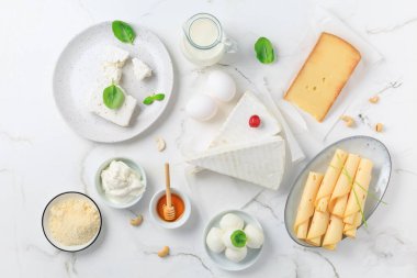 Beyaz mermer arka planda taze süt ürünleri. Peynir, bal, süt, yoğurt çeşitleri. Üst görünüm.