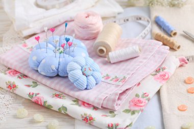 Dikiş aletleri ve malzemeler - el yapımı iğnelik, makas, iplikli bobinler, iğneler ve kumaş. Hobi, el işi, yaratıcılık, ev kavramında boş zaman..