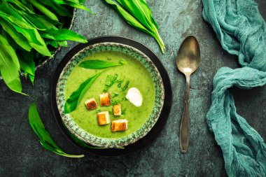 Ayı pırasa çorbası ya da ekmek arası Ramson çorbası, ekşi krema ve yeşil arka planda hindi şişi.