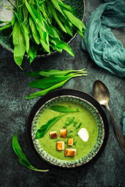 Ayı pırasa çorbası ya da ekmek arası Ramson çorbası, ekşi krema ve yeşil arka planda hindi şişi.