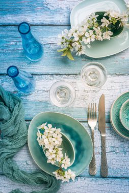 Denizcilik mavisi renginde kiraz dallarıyla donatılmış bir yer. Mutfak eşyaları ve masa ayarları.