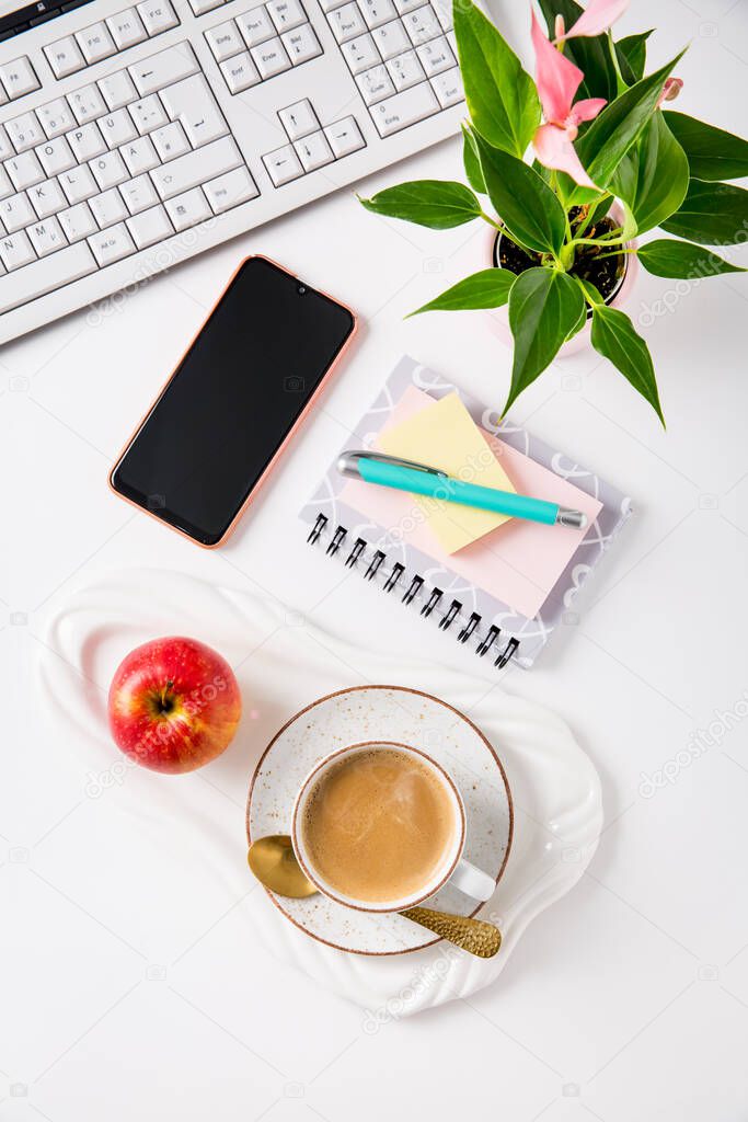 Workplace and office desk with coffee, apple, laptop, headset and smarthpone. Flatlay on white background.