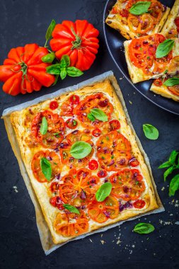 Vejetaryen domatesli tart ya da siyah arka planda otlu poğaçalı pizza.