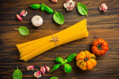 Akdeniz makarna tabağı - spagetti, domates, fesleğen, biber, ahşap zemin üzerinde sarımsak.