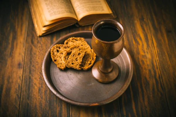 The sacrament of holy communion - bread, wine and bible on wooden table