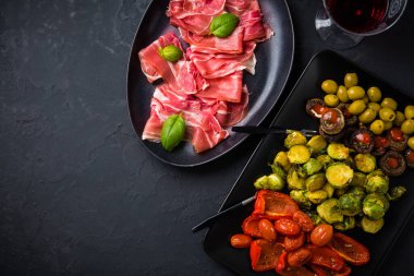 Siyah arka planda kırmızı şarap ve meze çeşitleri.