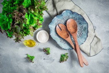 Modern seramik kâse ahşap salata çatal bıçak takımı ve taş zeminde bir kase marul.