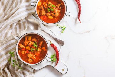 Gulaş çorbası. Beyaz arka planda kırmızı biber soslu sağlıklı Macar et ve sebze çorbası.