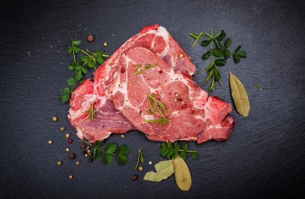 Frisches rohes Fleisch auf schwarzem Brett — Stockfoto