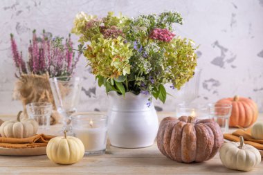 Şenlikli yemek masasında balkabağında güzel bir buket sonbahar çiçeği.