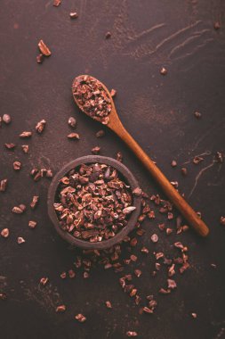 Kahverengi arka planda bir kasede organik kakao ve kakao çekirdeği.