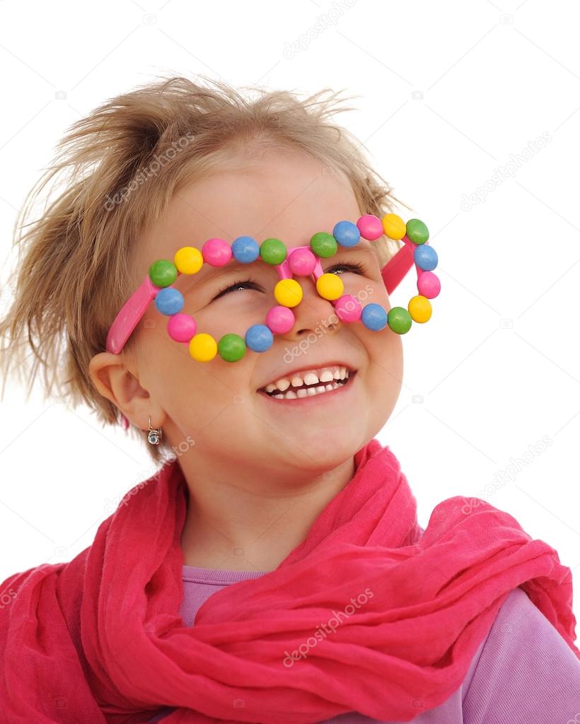 Portrait of cute little girl wearing funny glasses, decorated with colorful sweets, smarties, candies. Four years old child having fun, smiling