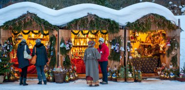 Karlı Noel Pazarı, yanan dükkanlar ahşap kulübelerde hediyeler ve el yapımı dekorasyonlar..