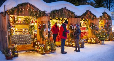 Karlı Noel Pazarı, yanan dükkanlar ahşap kulübelerde hediyeler ve el yapımı dekorasyonlar..