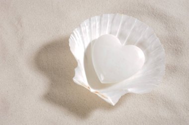 Beyaz kalp beyaz kumda yatıyor.