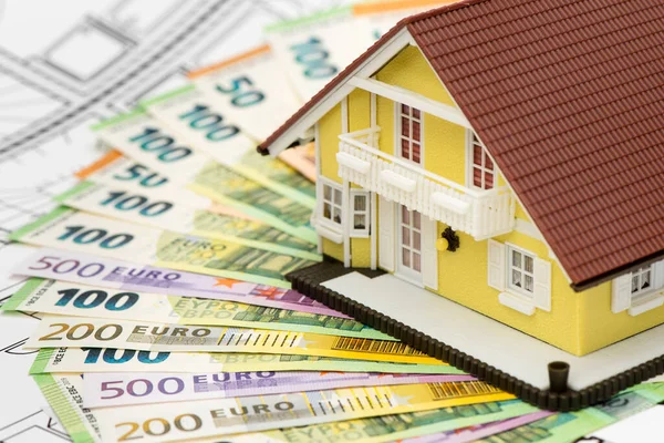 Euro banknotes laying under model home