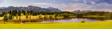 Allgaeu 'de dağ sırası, göl ve çayırla panoramik manzara