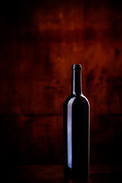 Láhev vína na tmavě červeném pozadí — Stock fotografie
