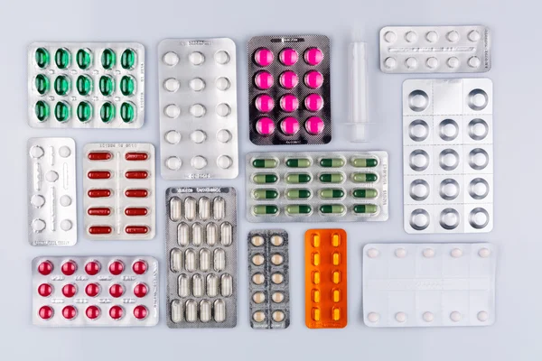 Many blisters with pills inside arranged on white — Stock Photo, Image