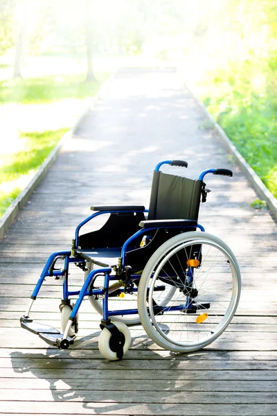 Cadeira de rodas na estrada que conduz à luz — Fotografia de Stock