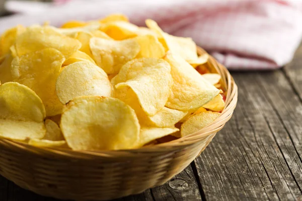 Crispy potato chips in a wicker bowl — Stock Photo, Image