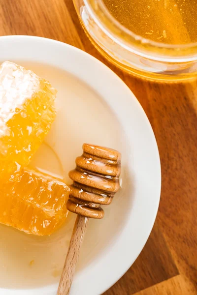 Palito de mel de madeira e favo de mel . — Fotografia de Stock