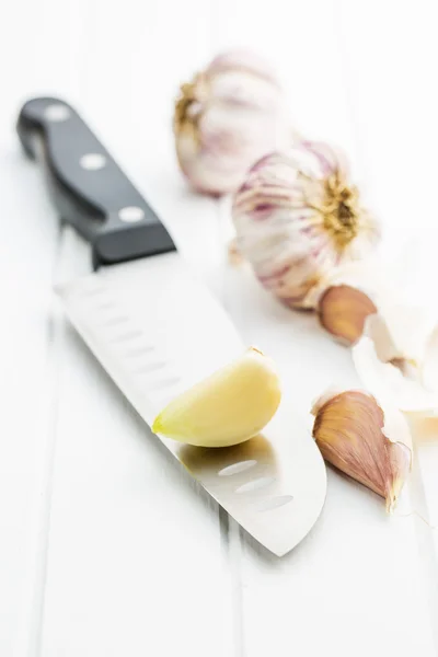 Peeled garlic on knife — Stock Photo, Image