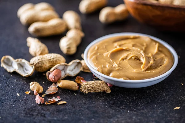 Jordnötssmör Skål Och Jordnötter Svart Bord — Stockfoto