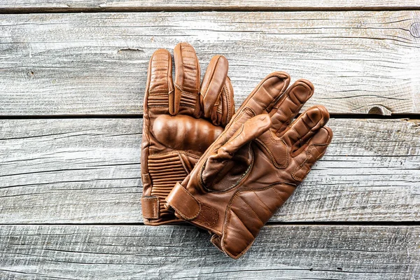 Brown leather motorcycle gloves on wooden table. Top view.