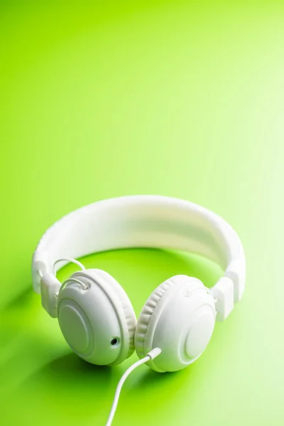 绿色背景的白色有线立体声耳机 — 图库照片