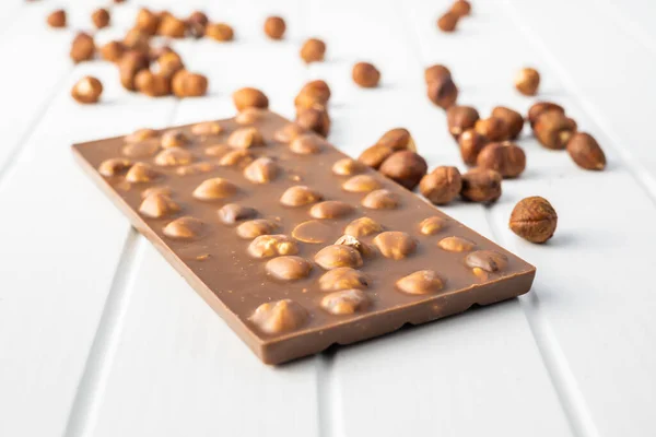 ホワイトテーブルの上にヘーゼルナッツとチョコレートバー — ストック写真