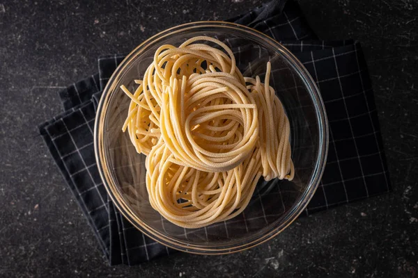 Olasz Tésztafészek Főzetlen Spagetti Fészek Tálban Fekete Asztalon Felülnézet — Stock Fotó