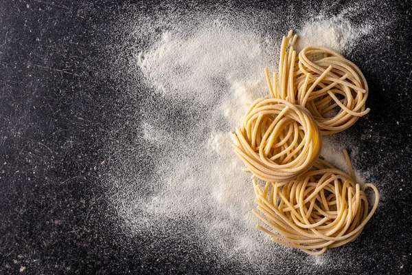 Italienisches Nudelnest Ungekochte Spaghetti Und Mehl Auf Schwarzem Tisch Ansicht — Stockfoto