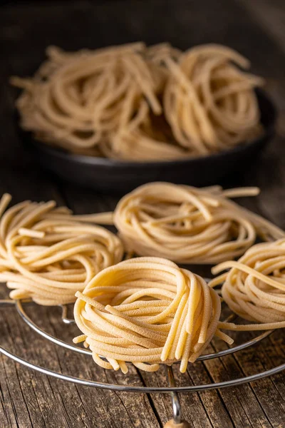 Italské Těstoviny Neuvařené Špagety Hnízdo Starém Dřevěném Stole — Stock fotografie
