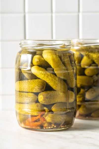 Small pickles. Marinated pickled cucumbers in jar on kitchen table.