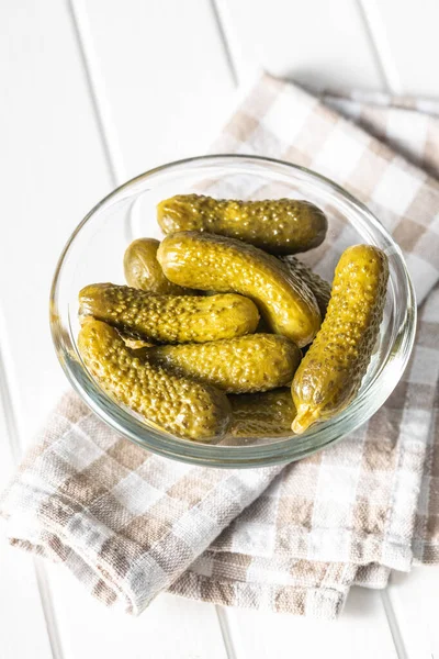 Small pickles. Marinated pickled cucumbers in bowl on checkered napkin.